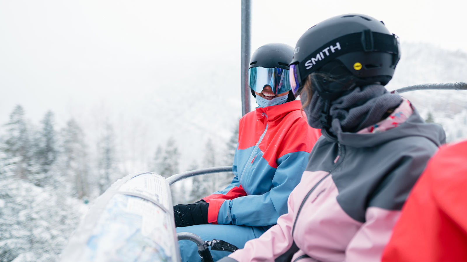 two girl friends smiling riding chairlift