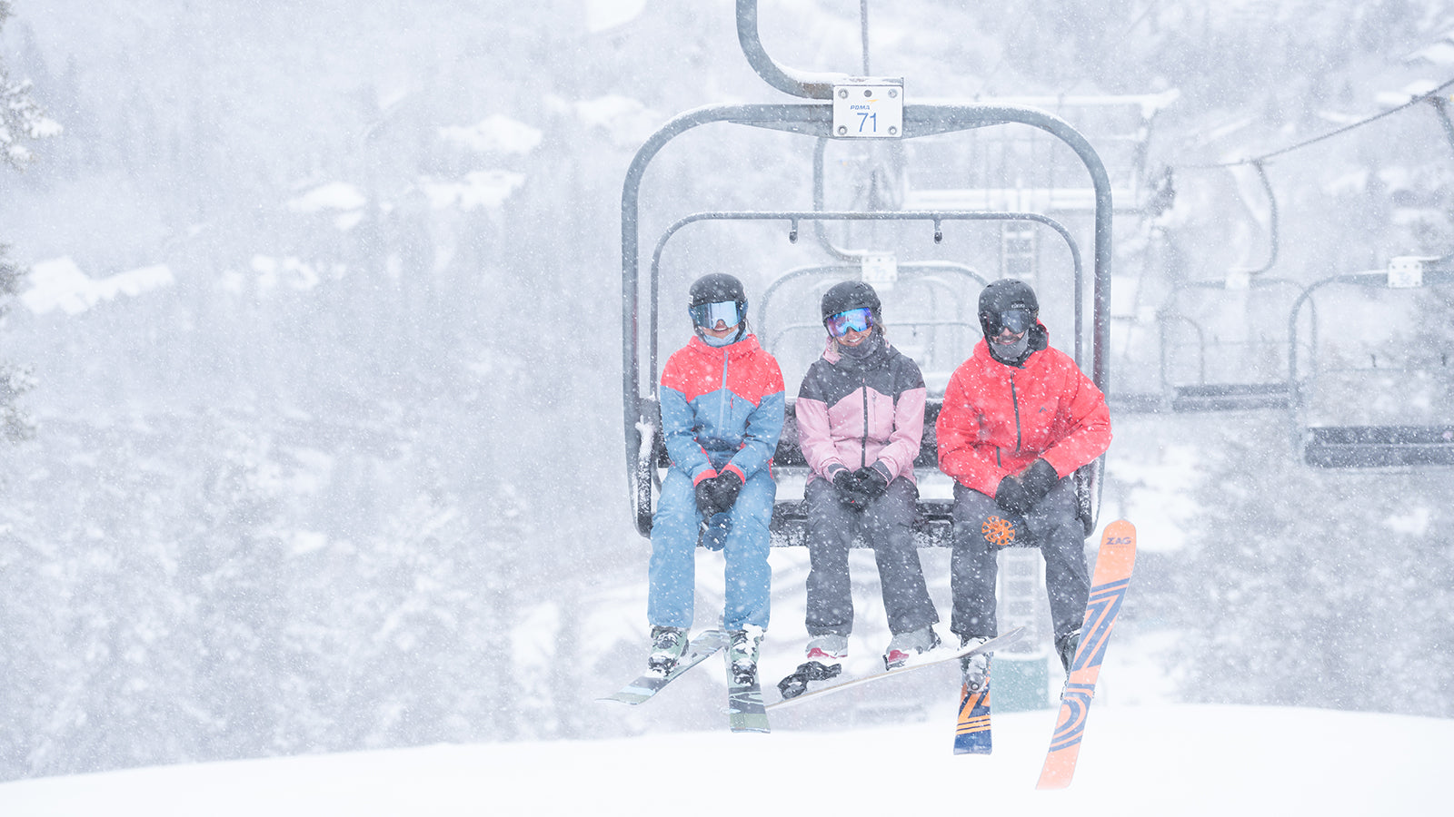 three friends riding snowy chairlift