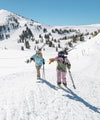 two women hiking carrying skis on shoulders